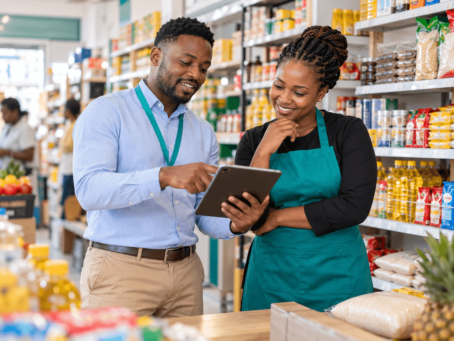 A distributor sales representative shows a retailer the order catalogue on a tablet